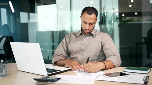 Focused serious businessman manager working at modern office workplace desk writing notes ideas