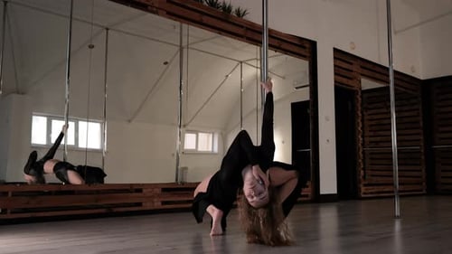 Joven atlética realiza trucos en pilón, bailarina de barra hace elementos acrobáticos, deporte moderno y