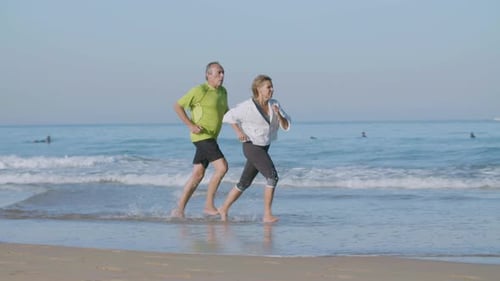 Woman Running Ahead Her Husband While They Jogging on Beach