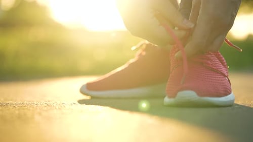 Woman Tying Shoelaces While Jogging or Walking at Sunset Slow Motion