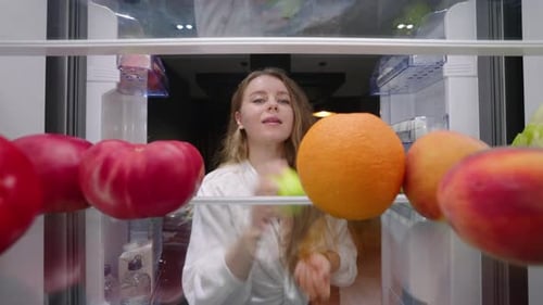 View From Inside Fridge Woman Opens Side By Side Fridge Doors Takes Fruits and Vegetables Closes It
