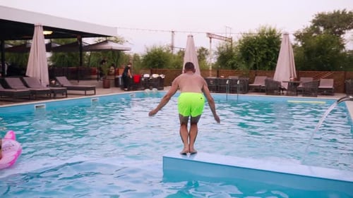 Mann springt ins Wasser und spritzt Tropfen im Luxusresort Kerl in Bademode Tauchen im Schwimmen