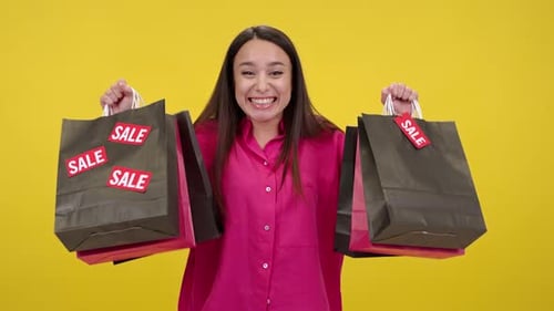 Woman Smiling with Sale Shopping Bags on Yellow