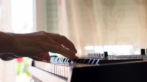 Backlit hand playing piano or midi controller at home. Composing music. Armonies.