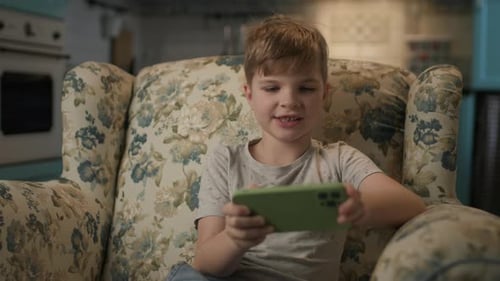 Boy Using Smartphone While Sitting in Chair