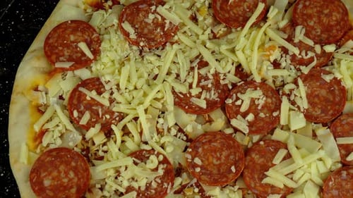 Top down view of a spinning pizza on a tray. Uncooked and ready for the oven.