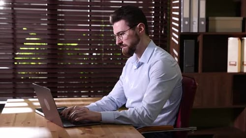 Handsome businessman working on laptop at wooden desk in office