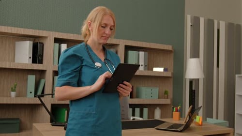 Focused Middle Aged Woman Nurse Networking Online on Tablet Pc at Hospital