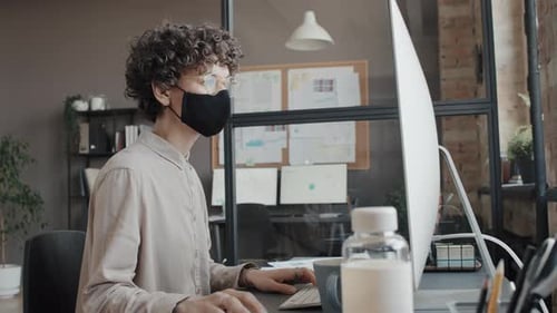 Femme masquée travaillant avec un ordinateur au bureau