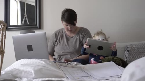 Mother and Child Working and Playing on Bed