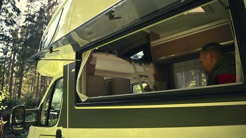 Man Sits in Camper Van in Forest