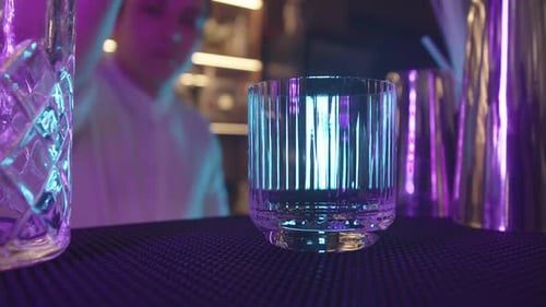 CloseUp of Glass on Table Bartender Add Big Square Ice Inside