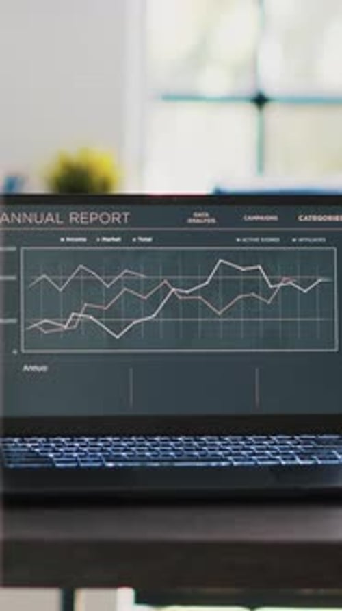 Vertical Video Business Graphs and Figures on Laptop Left Open on Desk in Empty Office