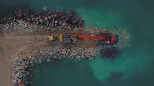 Hitachi EX1200 Super Long Reach Excavator moves stones from a truck into the sea to build a stone br