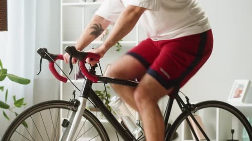 Legs of Sportsman Riding Bicycle Home Gym Young Man Cycling in Living Room Exercising in Morning