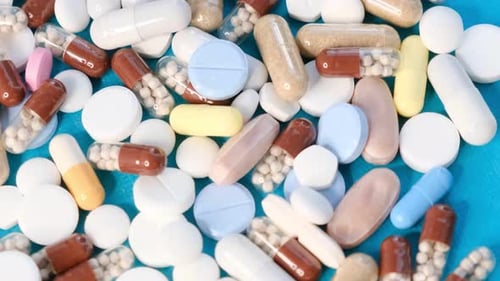 Pile of colorful pills and capsules on blue