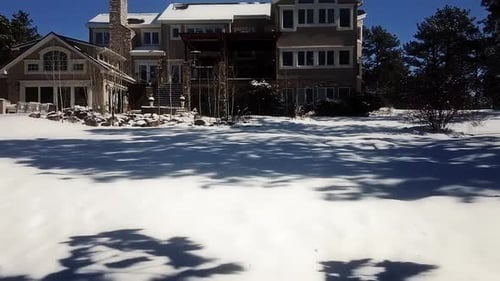 Drone shot through a gazebo, over the snowy yard and over the roof of a mountain mansion in the Blac
