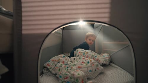 Un mignon bambin blond se cache dans une tente de jeu installée dans la chambre