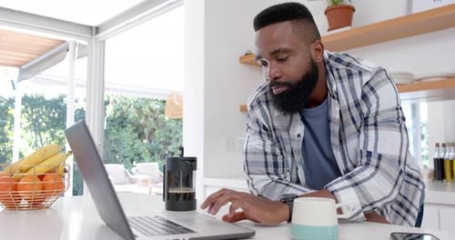Man Works on Laptop in Modern Kitchen