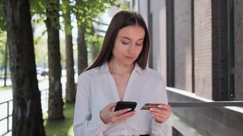 Woman Uses Phone and Credit Card on Street