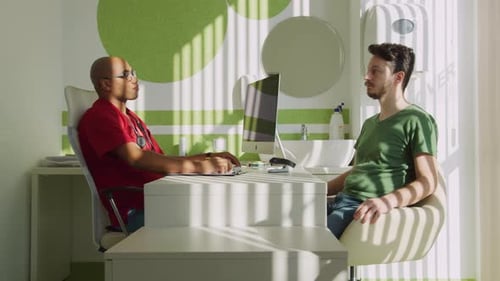 Doctor Consults with Young Adult Patient in Office