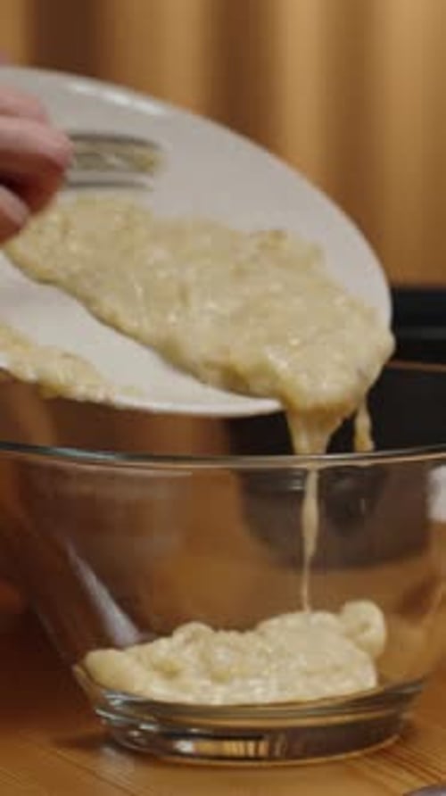 Vertical video. The recipe for banana cake involves pouring the prepared banana puree.