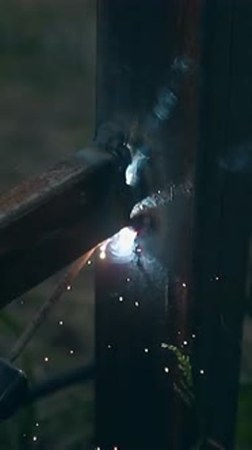 Slow Motion Closeup Man Builds Fence with Welding Machine