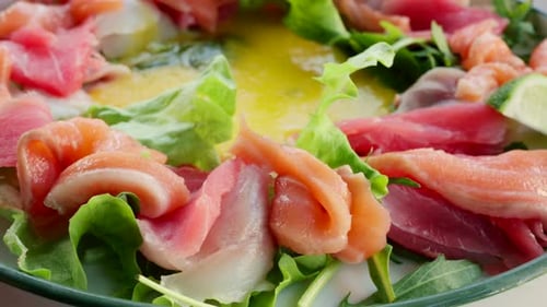 Close up of fresh raw fish slices with greens in a salad