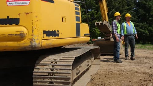 Construction Workers Meeting and Talking on Job Site Backhoe