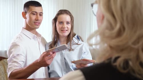 Young Couple Gives Passports to Receptionist for Reserve Room