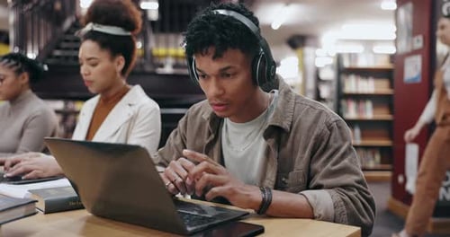 Man, reading and headphones with laptop in library for typing assignment essay