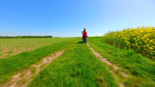 FPV of Caucasian Woman Riding a Vintage Motorcycle Through Summer Meadows
