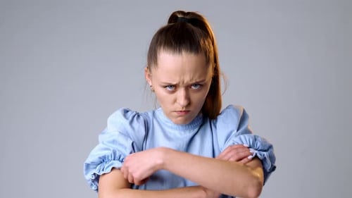 Сapricious Offended Young Woman Against Gray Background