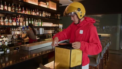 Mensajero masculino tomando una bolsa de comida de una trabajadora de bar para entregarla