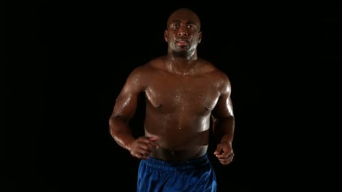 Sweaty man running in place against black backdrop
