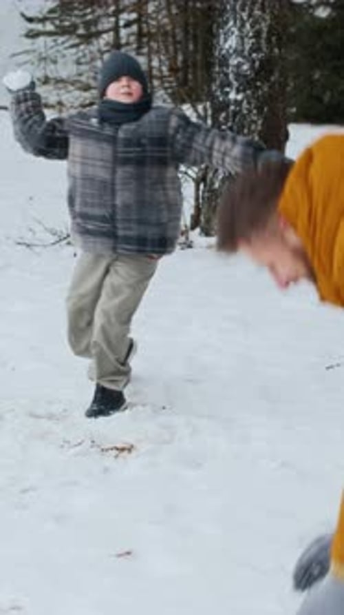 Dad and Son Playing Snowballs in Winter Forest