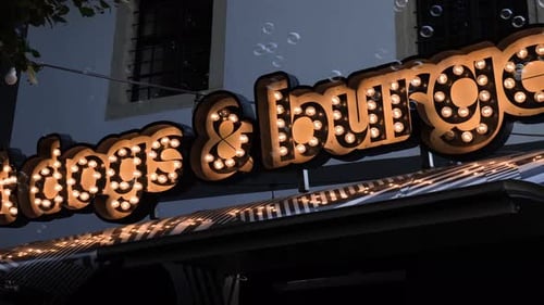 Illuminated Hot Dogs And Burgers Store Sign With Bubble Generator. low angle, pan right