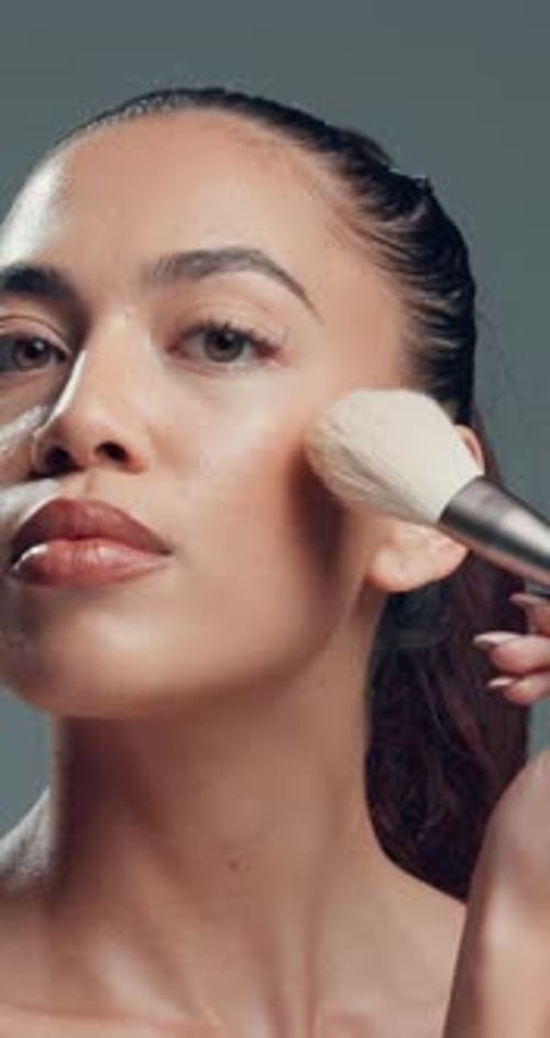 Face, woman and brush for makeup in studio for beauty, foundation application and aesthetic
