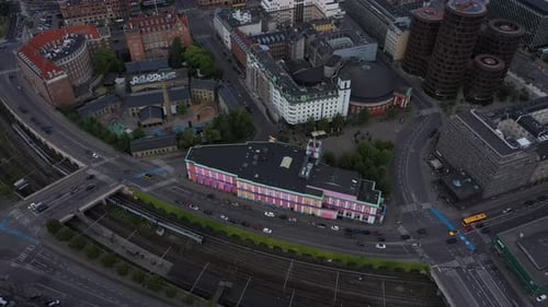 Aerial panning shot of train by street and buildings in city, drone flying over cityscape - Copenhag