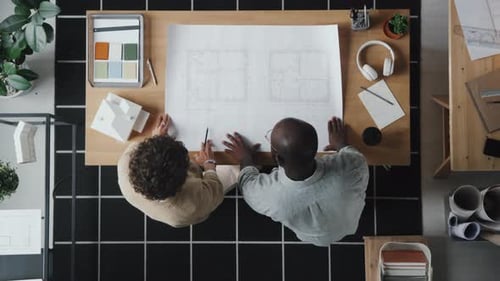 Architects Reviewing Building Blueprint Together in Workplace