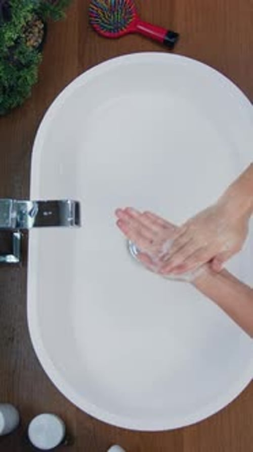 Woman Washing Hands with Soap in Bathroom Sink