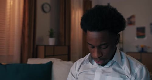 Worried Young Adult Sits on Couch at Night