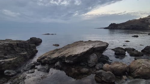 Sea Rocks Coastline Calm Dark Ocean Waves Gently Wash Rugged Cliff Shore Under Moody Overcast Sky