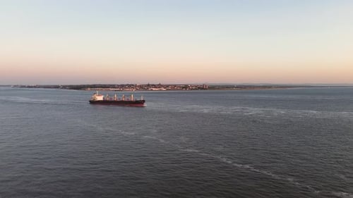Aerial view of a cargo vessel in the sea in sunset time leaving and entering container port