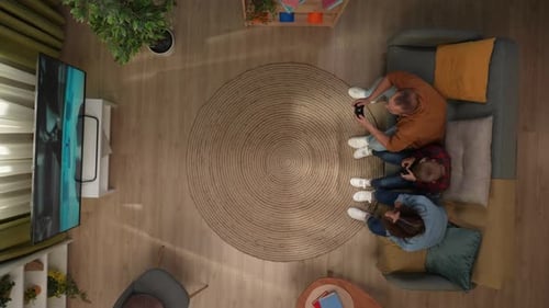 Top View of Living Room Mother Father and Son Sitting on the Sofa Playing Video Game on Tv Dad Won