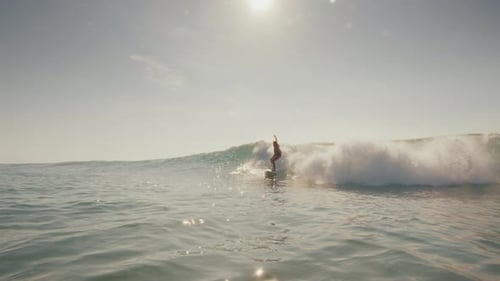Male Surfer Riding Ocean Wave on Sunny Day