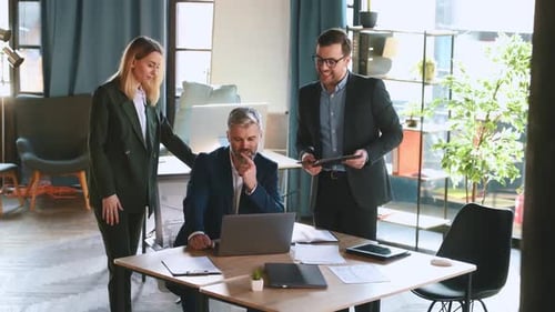 By the table, talking about project. Business people are working in the office together