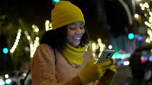 Young Woman Using Smartphone on City Street at Night