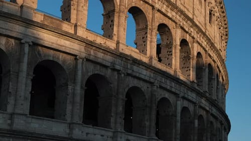 Sunrise shadows falling across roman Colosseum Italian stone amphitheatre ruin window arches