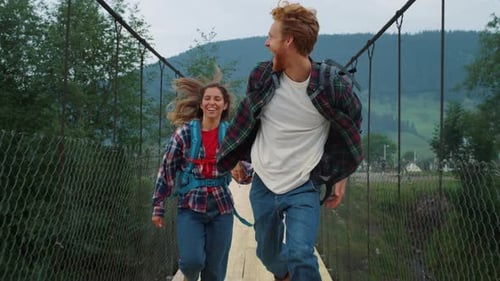 Emotional Couple Travelers Running on Mountains Bridge. Smiling Hikers Racing Fast Outside